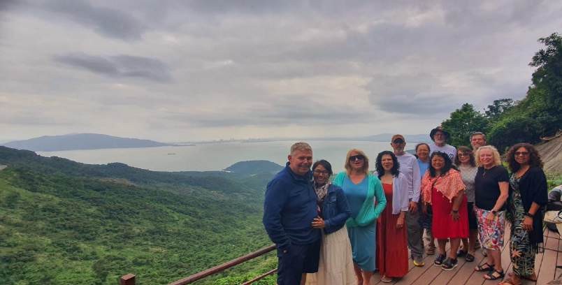 A group of people standing on a wooden deck Description automatically generated